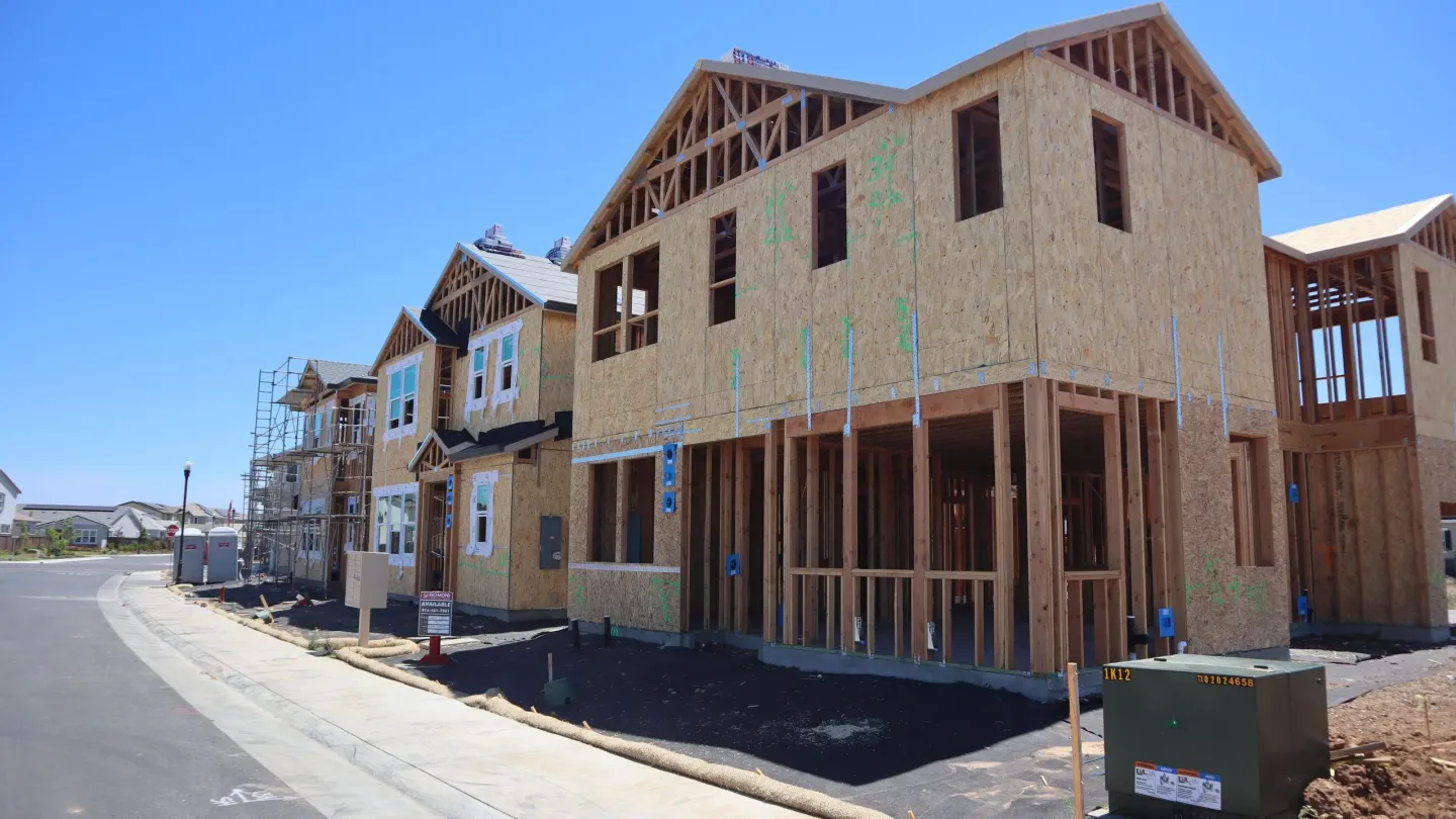 A new residential street with timber-framed houses at different stages of construction.