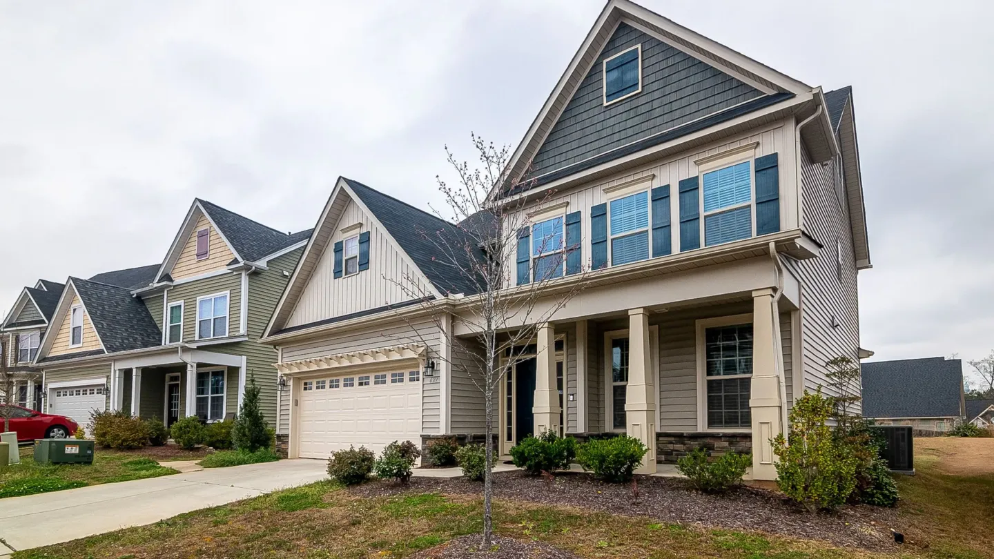A row of newly built two-storey suburban homes with garages and fresh landscaping.